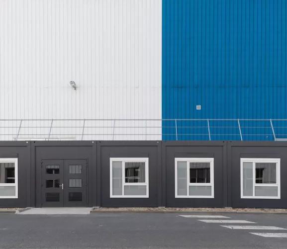 Façade d'un bâtiment industriel avec extension modulaire grise et bleue ALGECO®