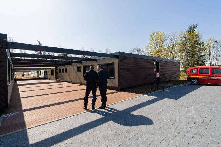 Deux personnes de dos en discussion devant une construction ALGECO® avec habillage bois et cour extérieure 