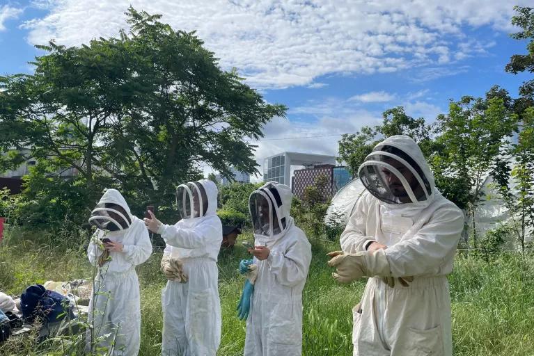 personnes en tenue d’apiculteurs en plein air