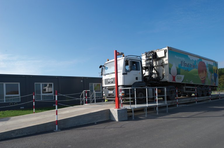 camion de livraison garé sur rampe en béton et barrières de sécurité métalliques à côté de bâtiments modulaires ALGECO®