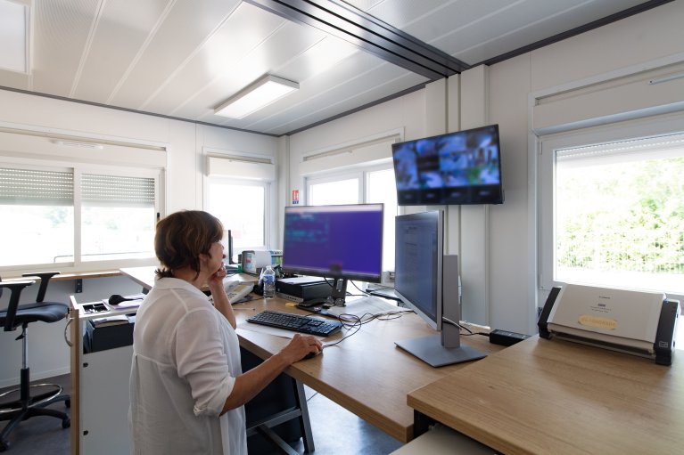 bureau modulaire moderne ALGECO® avec une personne travaillant à son poste de travail et vidéosurveillance.