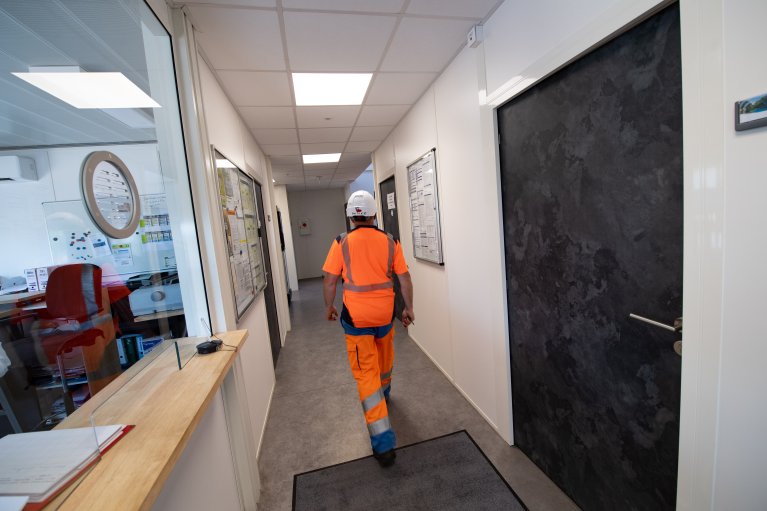 Ouvrier en tenue de sécurité marchant dans un couloir de bâtiment modulaire ALGECO® 