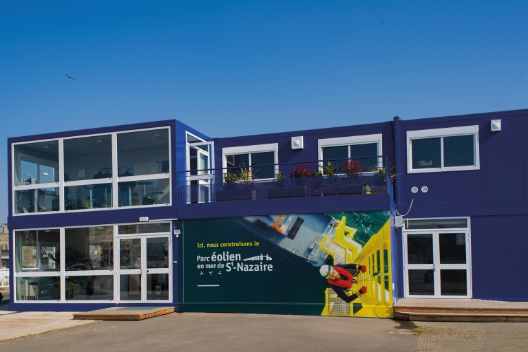 Bureaux modulaires temporaires bleus ALGECO® sur deux étages avec baies vitrées et affichage pour le Parc éolien en mer de S-Nazaire