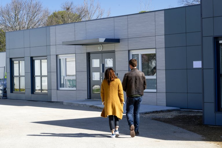 Personnes marchant vers un bâtiment moderne de bureaux modulaires ALGECO®