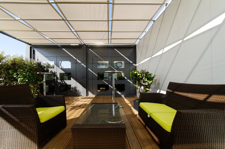 Terrasse extérieure modulaire aménagée ALGECO® avec meubles en rotin