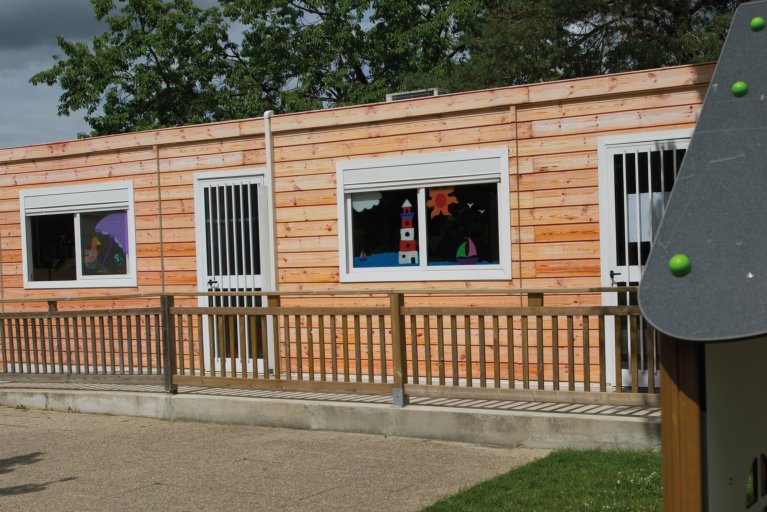 crèche modulaire ALGECO® avec barrière et bardage en bois et fenêtres décorées