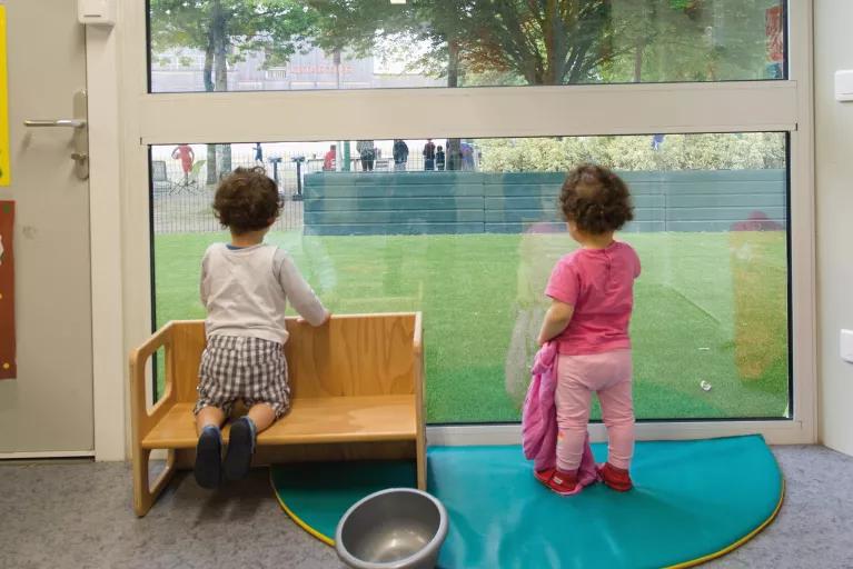 Enfants regardant vers l’extérieur d’une crèche modulaire ALGECO®