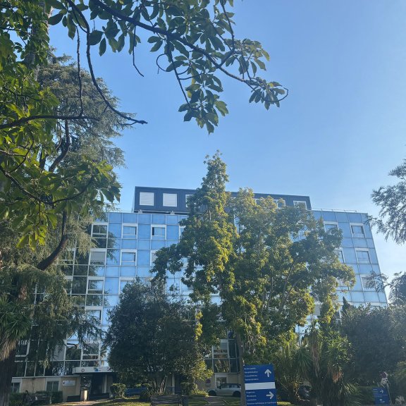 façade de l’hôpital La Palmosa de Menton derrière les arbres avec bureaux modulaires ALGECO® sur le toit